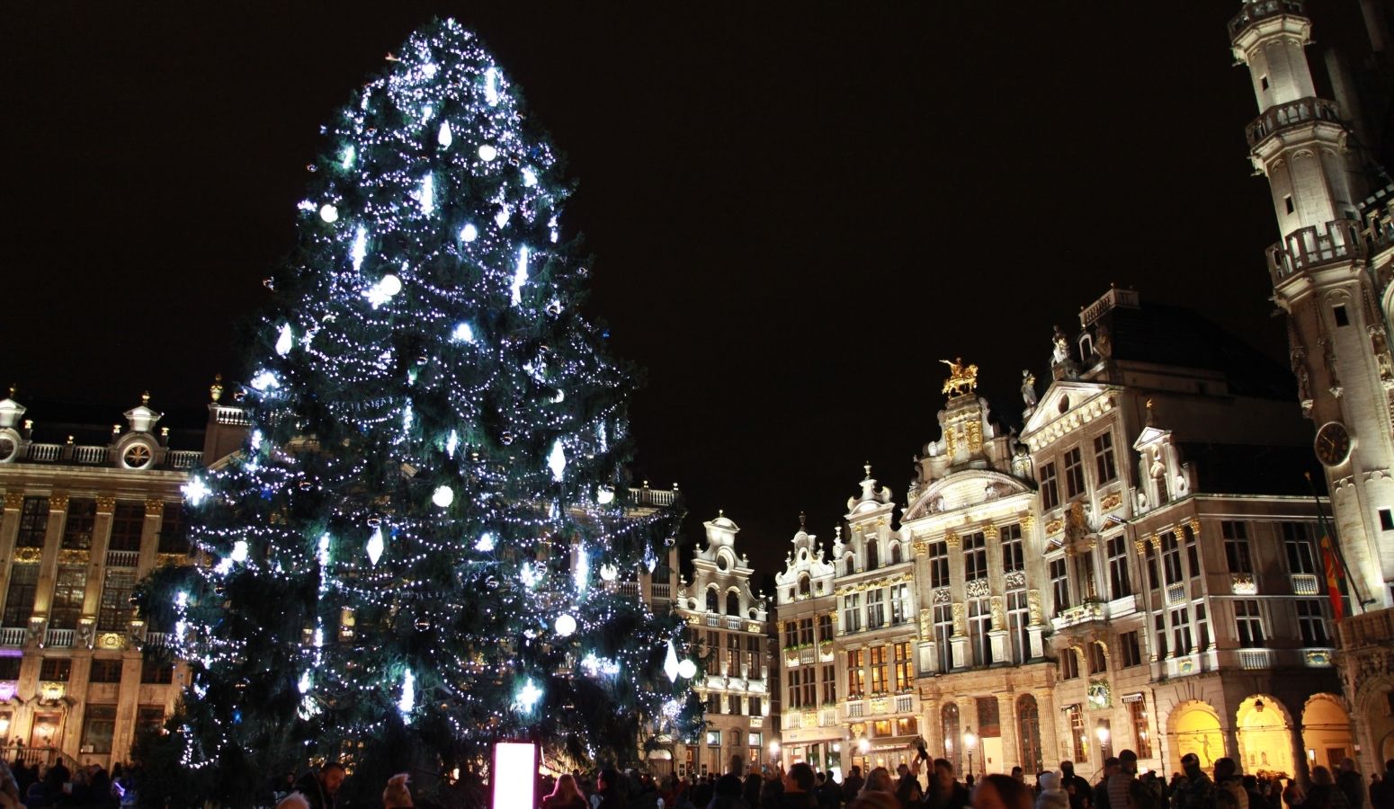 Árbol de Navidad iluminado en la Grand Place de Bruselas, rodeado de edificios históricos, durante los mercadillos navideños del Puente de Diciembre en Flandes.